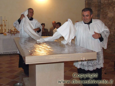 Il Parroco e il Cerimoniere vescovile coprono l’altare appena consacrato con una tovaglia di lino ricamata.